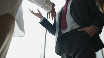 Wall Mural - Close-up of two business partners shaking hands to signify an agreement in the office against the window