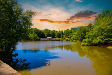 A Gorgeous Summer Landscape In The Park With A Silky Green Pond Surrounded By Lush Green Trees, Grass And Plants With Powerful Clouds At Sunset At Mill Creek Pond In Alpharetta Georgia USA