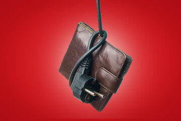 An electric cord with a plug tied in a knot on an old wallet. The concept of the energy crisis