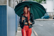 Girl With Umbrella And Mobile Phone Walking On The Street