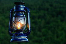Kerosene Lantern Lamp With Bright Flame With Green Forest In The Background
