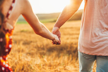 Close Up Outdoor Portrait Of Couple Holding Hands In The Wheat Field. Symbol Of Love And Happy Relationship. A Loving Couple Holding Hands. Romance. Summer