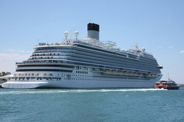 Modern cruise ship and boat in sea on sunny day