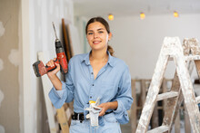 Portrait Of Smiling Young Woman With Drill In Apartment During Renovation Works.