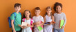 Group of little children with copybooks on orange background