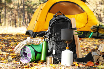 tourist's survival kit and camping tent in autumn forest