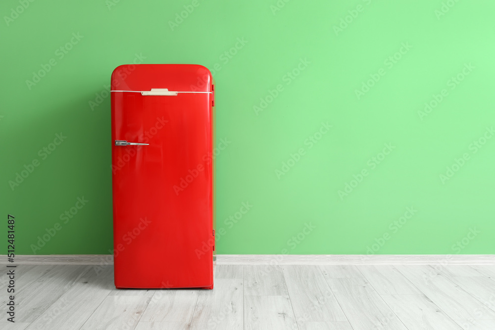 Stylish retro fridge near green wall in room