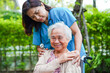 © manassanant - Doctor help Asian elderly woman disability patient sitting on wheelchair in park, medical concept.