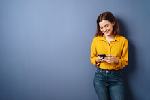 Woman Looking At Her Cell Phone Laughing, Copyspace With Blue Background