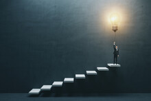 Innovation And Idea Concept With Front View On Businessman In Suit On The Top Of White Stairway Turning On Big Light Bulb On Dark Concrete Background In Empty Hall