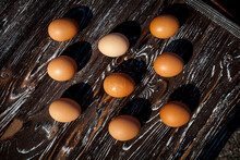 A Symmetrical Composition Of Nine Raw Brown Chicken Eggs On A Dark, Textured, Wooden Table In The Kitchen.