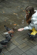 Little cute girl feeds pigeons outdoors. 