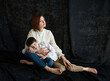© Tetatet - smiling mother and child hugging on black background in studio