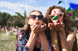 © gpointstudio - Two young caucasian women blowing confetti towards camera on music festival
