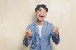 young asian man wearing college suit with excited expression