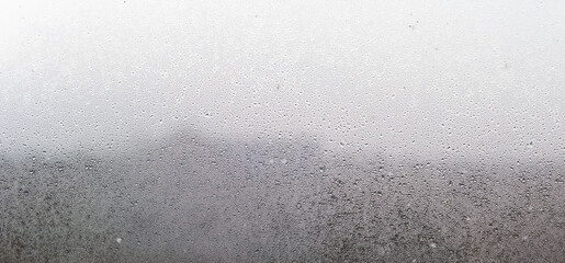 Closeup shot of a steamy window with water drops made in dull day.