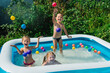 © Serhii - Three happy friends are splashing in an inflatable pool in the garden. Concept of summer season and recreation. Kids having fun together. Children playing and swimming in water on the backyard.