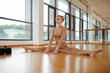 © DragonImages - Fit female dancer doing side splits to stretch legs before training