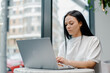 © Guys Who Shoot - Young Caucasian business woman with long brunette hair working on laptop in cafe. College student using technology , online education, freelance