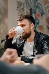 Wall Mural - The Man drinks coffee in the company of cheerful friends who communicate on weekends and spend time together at lunch in the dining room. Meeting in a public place. Friendship.