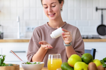 Poster - vitamins, nutritional supplements, healthy lifestyle concept. young woman eating breakfast and takin