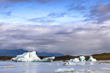 Wall Mural - fjallsarlon glacier lagoon, iceland. blue icebergs float and are reflected in the water. part of the