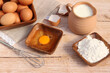 Backzutaten Eier, Milch und Mehl auf einem Holztisch.