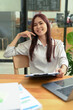 © Prathankarnpap - Cheerful asian female employee sitting at her office desk and smiling at camera