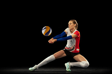 Dynamic portrait of professional volleyball player in sports uniform playing volleyball isolated on dark background. Sport, healthy lifestyle, team, action, motion concept