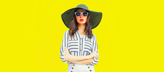 Portrait of beautiful woman model wearing black round summer hat, white striped shirt on yellow background