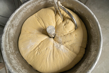 Close-up of kneading elastic dough for bread in a kneading machine in a bakery. Industrial mixer for kneading dough.