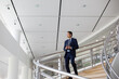 © ReeldealHD images - Businessman walking down spiral staircase in office with smartphone
