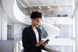 © ReeldealHD images - African American businesswoman using a smartphone in modern corporate office atrium