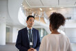 © ReeldealHD images - Asian businessman meeting with a coworker in the office atrium