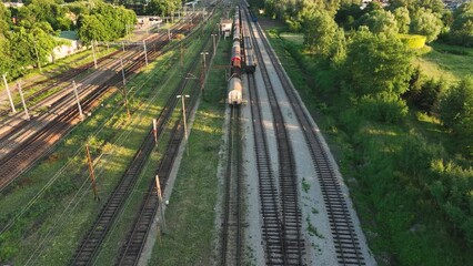 Poster - The view from the drone on the railroad tracks against the background of the setting sun. Concept of train traffic, rail transport, passengers. Aerial view of tracks, freight trains, train station.