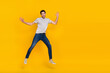 © deagreez - Full size photo of cool brunet young guy run jump wear t-shirt jeans footwear isolated on yellow background