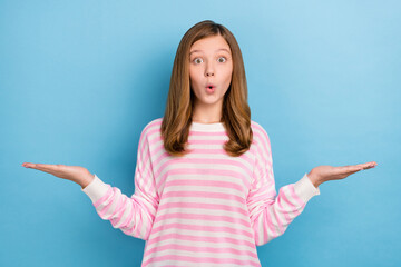 Poster - Photo of impressed teenager girl hold empty space wear white shirt isolated on blue color background