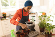 © Wavebreak Media - Biracial young woman in hijab putting soil in pot on table at home