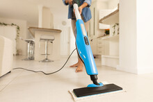 Low Section Of Biracial Young Woman Cleaning Tiled Floor In Living Room With Vacuum Cleaner At Home