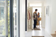 © Wavebreak Media - Multiracial young couple with grocery bags talking while entering inside house, copy space