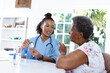 © Wavebreak Media - African american female doctor giving medicines to senior patient while sitting at table at home