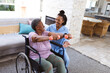 © Wavebreak Media - African american doctor guiding senior woman exercising with dumbbells while sitting on wheelchair