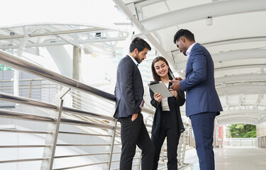 young multiracial business people standing on walkway building in the urban casual working and discussing with tablet  together