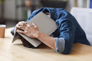 Depressed Young Man Sitting At Desk And Covering His Head With Laptop