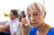 Close-up portrait of asian senior woman wiping her tears with multiracial friends in background