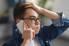 Worried Young Man Talking On Cellphone And Touching Head In Stress