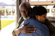© wavebreak3 - Multiracial senior man with eyes closed embracing woman while standing in nursing home