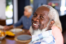 Close-up Portrait Of African American Senior Man With Multiracial Friends Sitting At Dining Table