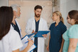 © Kostiantyn - Group of doctor colleagues discussing patient diagnosis stand in clinic hall