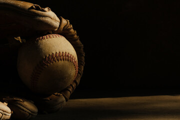 Sticker - Old baseball glove with ball on black background with copy space for sports banner.